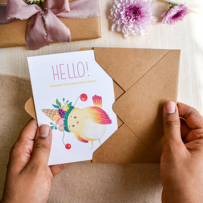 Hello greeting card with bird wearing fruit hat in kraft paper envelope